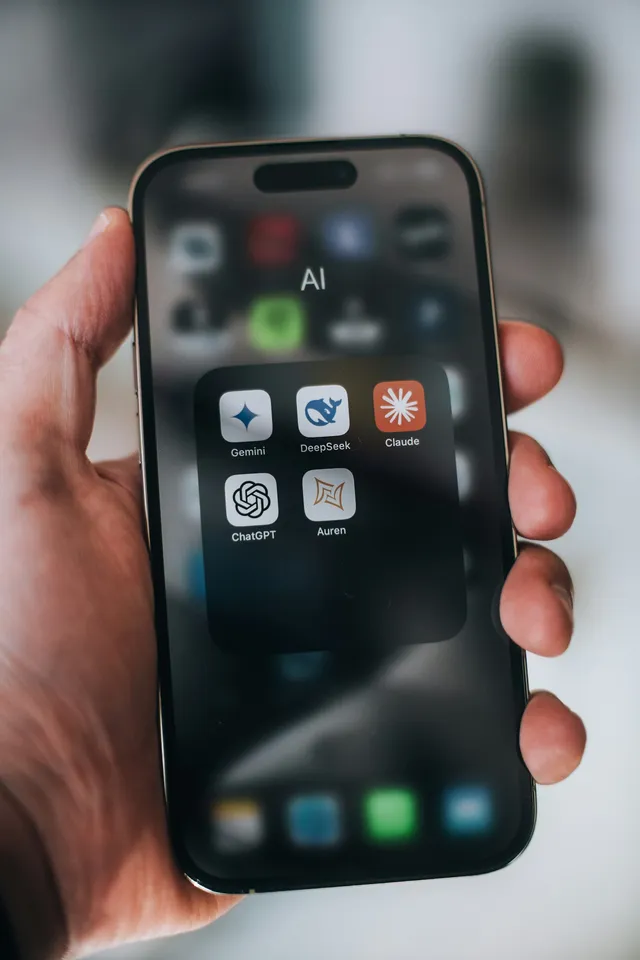 Mão segurando smartphone com ícones de aplicativos de inteligência artificial
