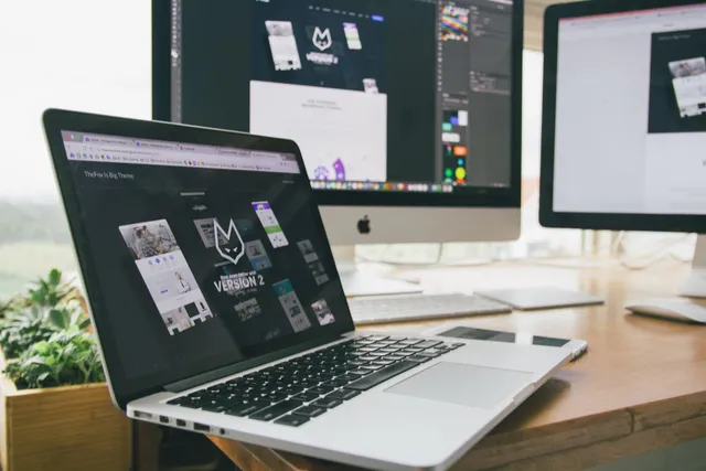 Notebook e monitores exibindo layout de site em mesa de escritório