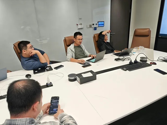 Quatro pessoas em sala de reunião trabalhando com notebooks