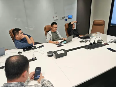 Quatro pessoas em sala de reunião trabalhando com notebooks